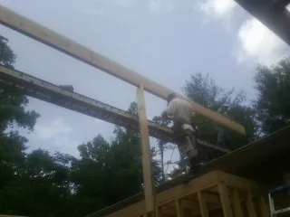 Carpenter setting a ridge beam over a new addition frame — Ice Dam Removal by Roofing Brothers in Oakhurst