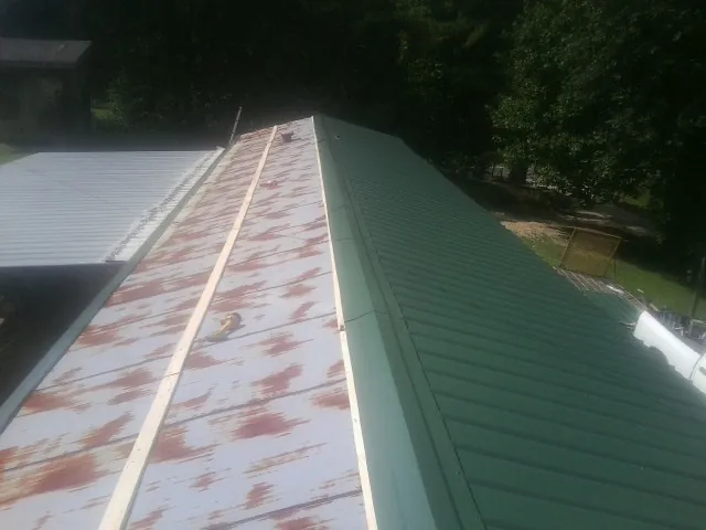 Old rusted panels beside newly installed green metal roofing — Wind Damage Roof Repair by Roofing Brothers in Oakhurst