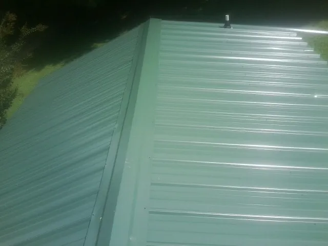 New green metal panels meeting at the ridge of a roof — Flat Roof Repair work by our crew in Oakhurst