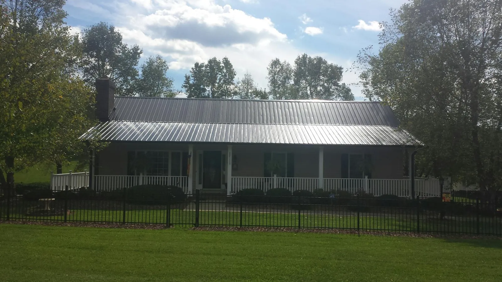 Gray metal roof on a brick ranch with a full width front porch — Gutter Guard Installation work by our crew in Oakhurst
